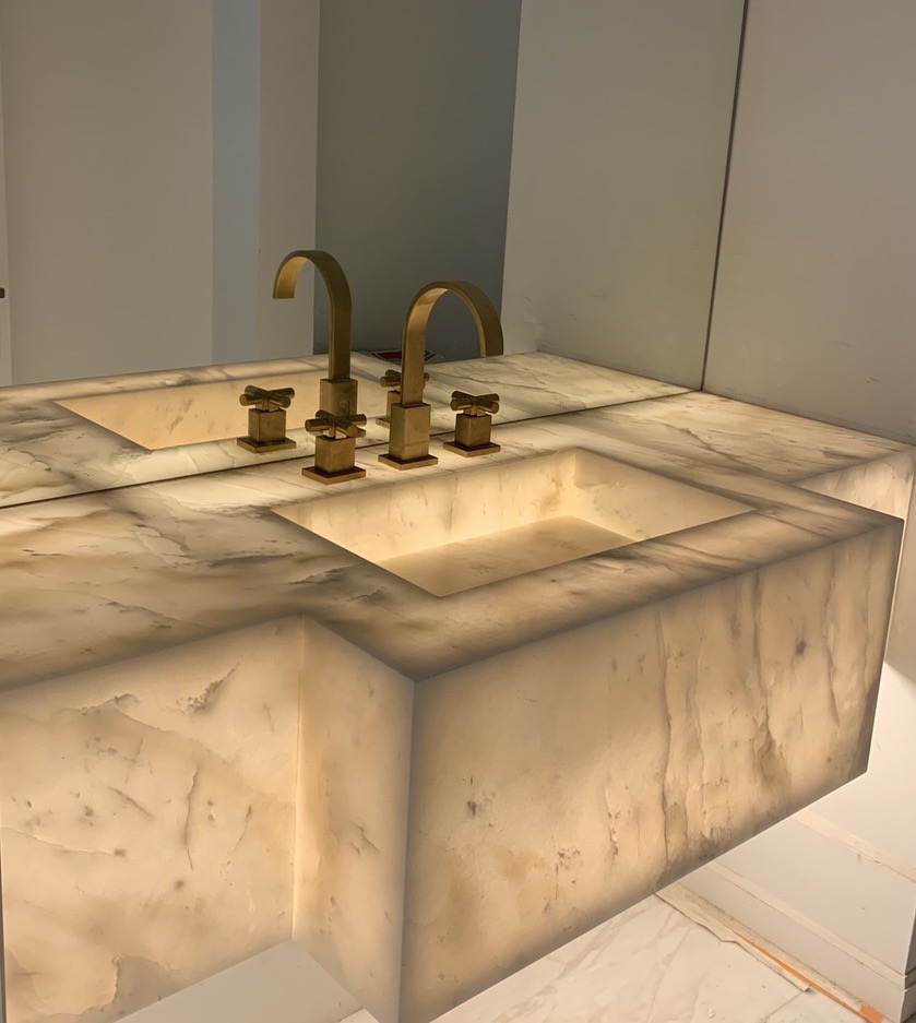 Backlit alabaster vanity with brass fixtures - translucent stone glowing from within.