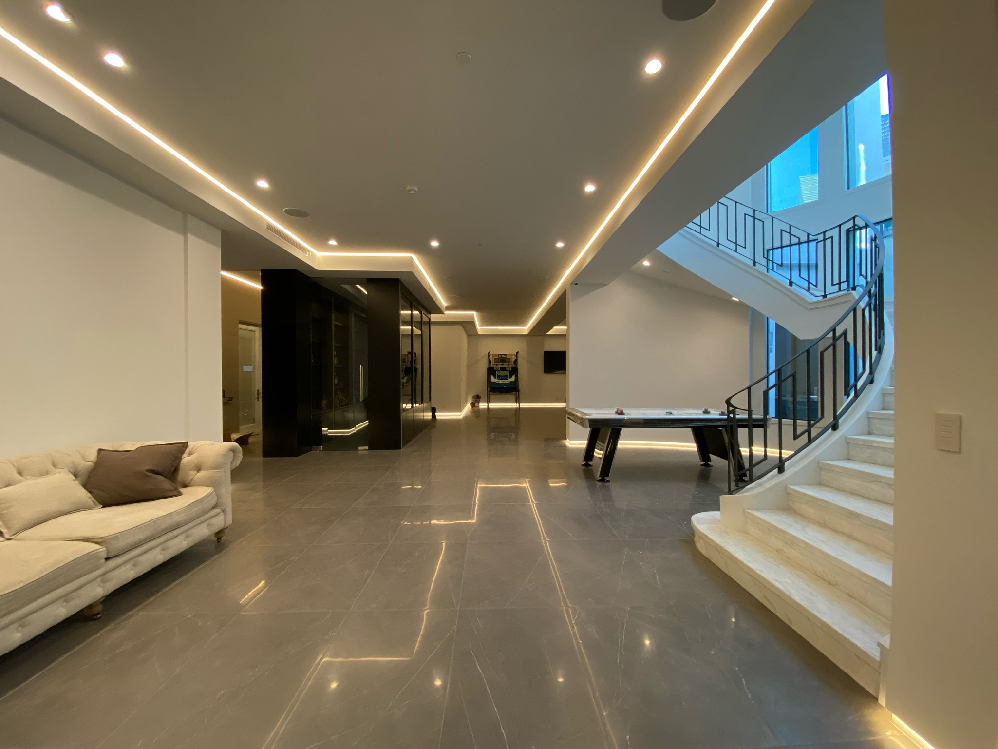 Concealed linear lighting tracing a tray ceiling and toe kick along a luxury residential corridor.